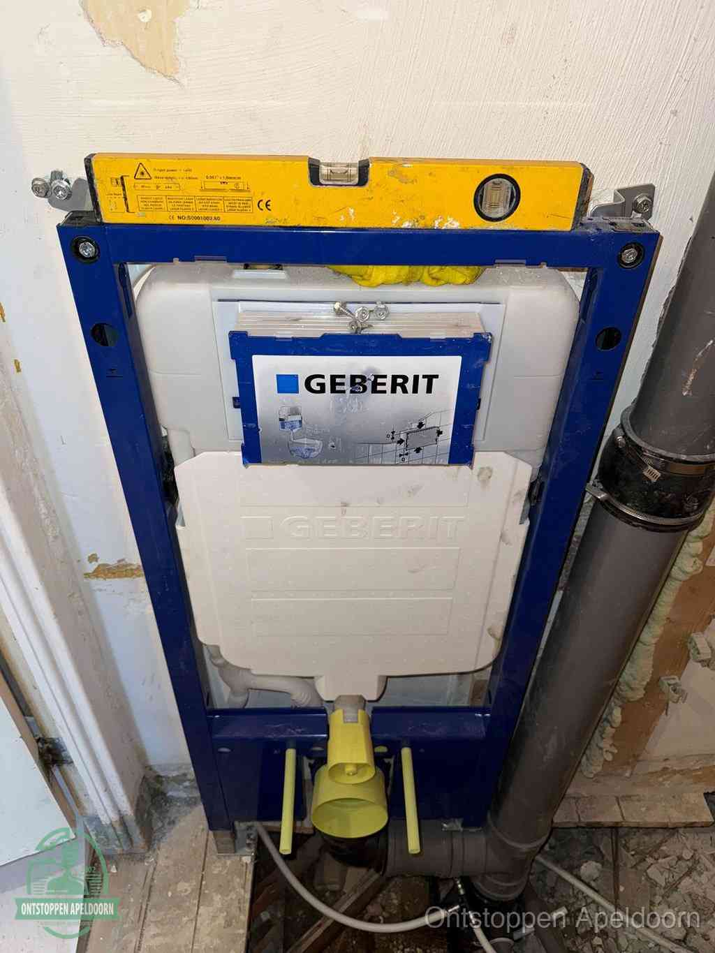 Een Geberit inbouwreservoir met frame voor een hangtoilet tegen de wand, met de afvoerbocht naar de vloer, kenmerkend voor een verstopt hangtoilet in Apeldoorn