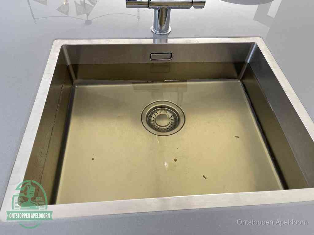 Stilstaand water in een rvs spoelbak dat niet wegloopt, een duidelijk signaal van een gootsteenverstopping in Apeldoorn