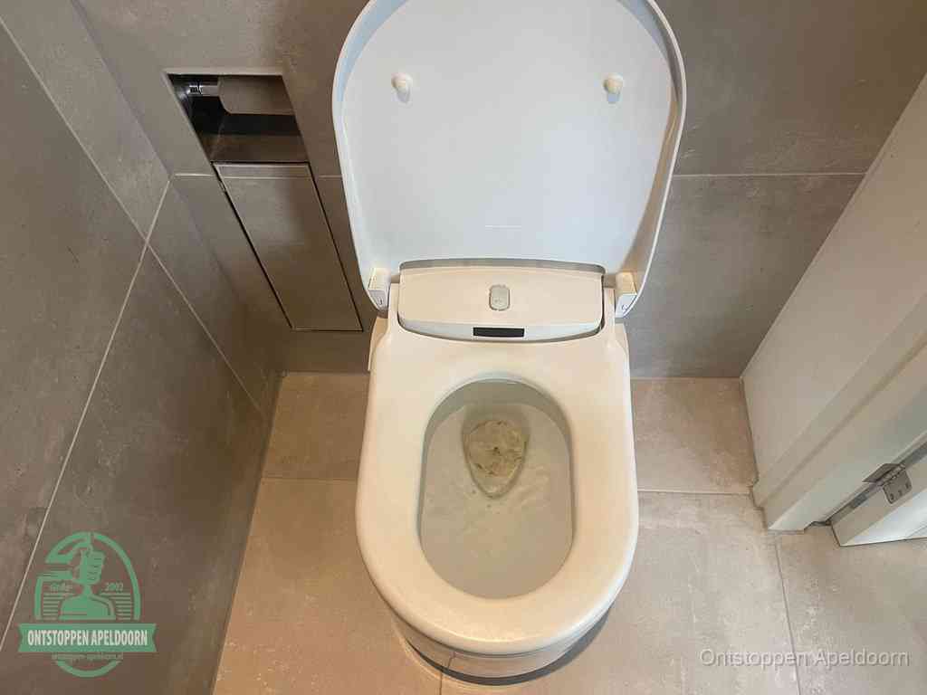 Een wit hangtoilet waarin een prop wc-papier op het water blijft drijven, een duidelijk signaal van een verstopte wc in Apeldoorn