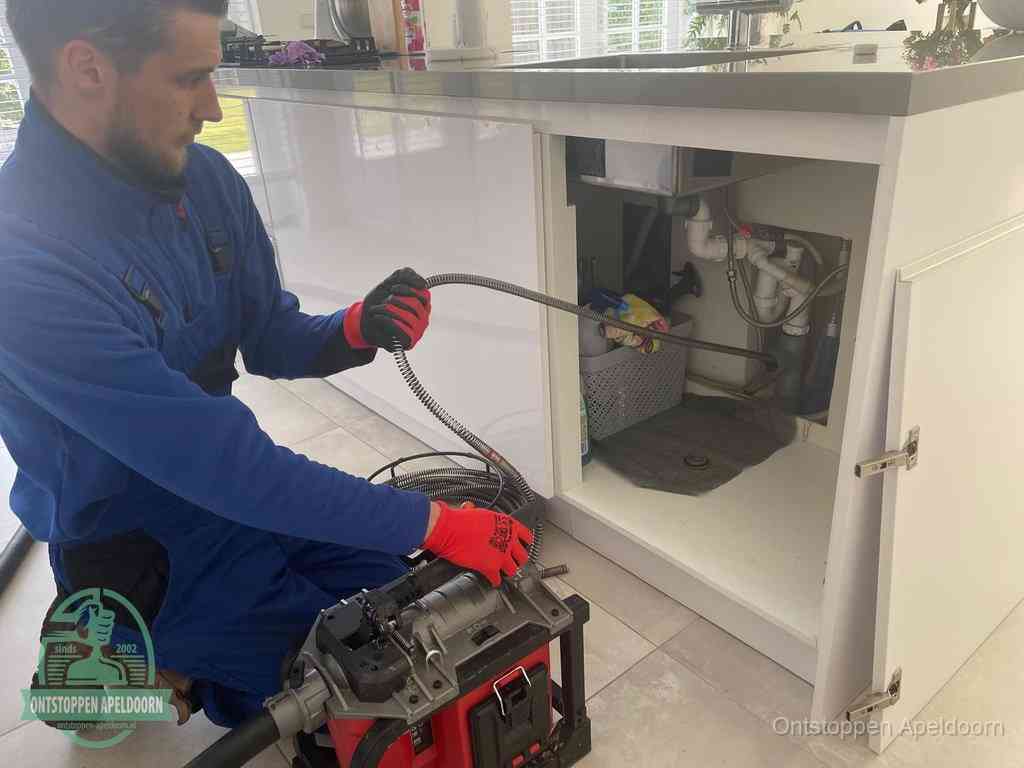 Een monteur reinigt de keukenafvoer grondig met een veermachine om terugkerende gootsteenverstoppingen te voorkomen in Apeldoorn