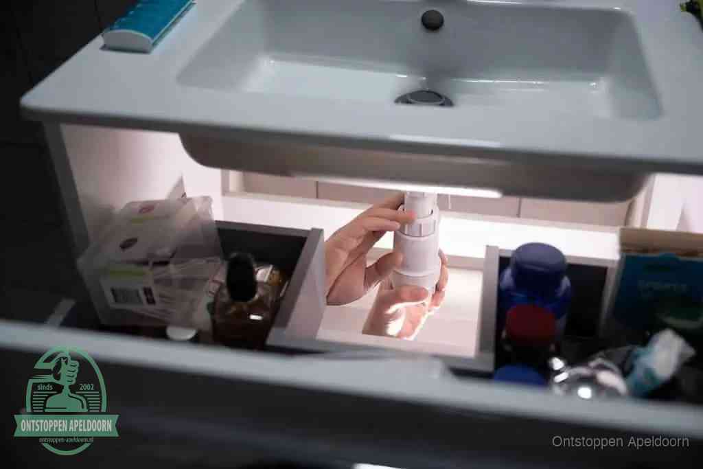 Een pompfles met zeep boven een wastafel in de toiletruimte, de warm water en afwasmiddel-methode om de wc te ontstoppen in Apeldoorn