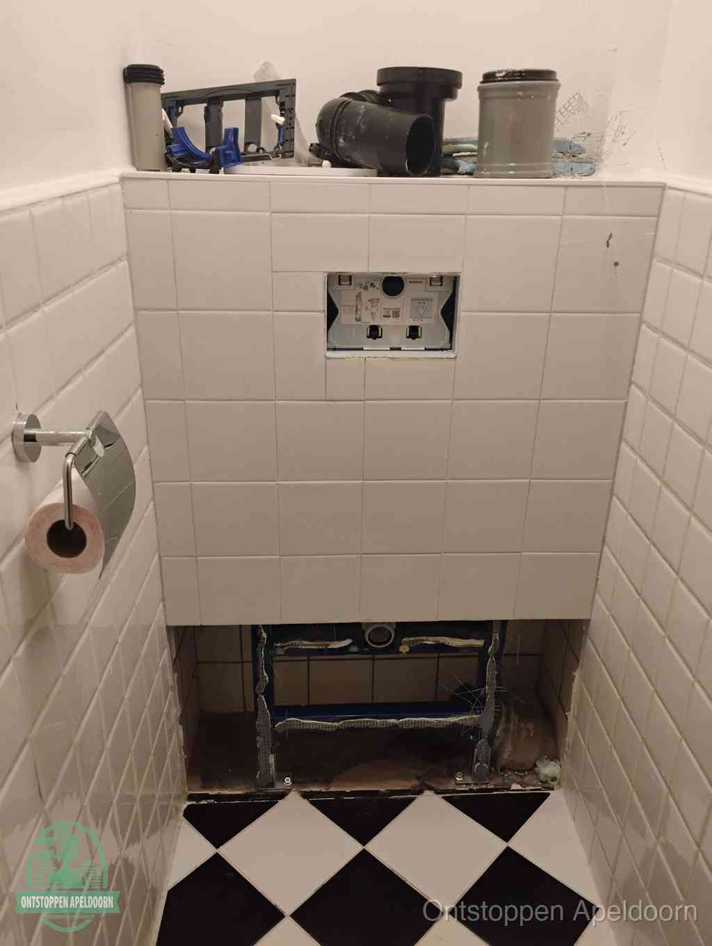 Een toiletruimte waar het hangtoilet en de inbouwreservoir-onderdelen zijn vrijgelegd voor onderhoud, periodiek nazicht voorkomt een wc-verstopping in Apeldoorn