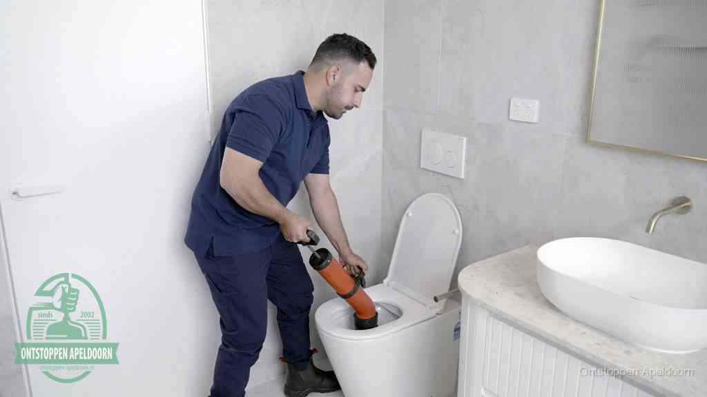 Een monteur gebruikt een handmatige perspomp (toiletontstopper) op een wandcloset tijdens het professioneel wc ontstoppen in Apeldoorn