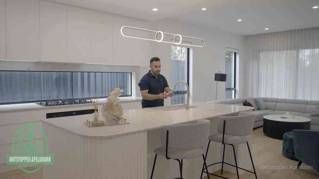 Een bewoner bij de keukenspoelbak die zelf aan de slag gaat met een verstopte gootsteen in Apeldoorn